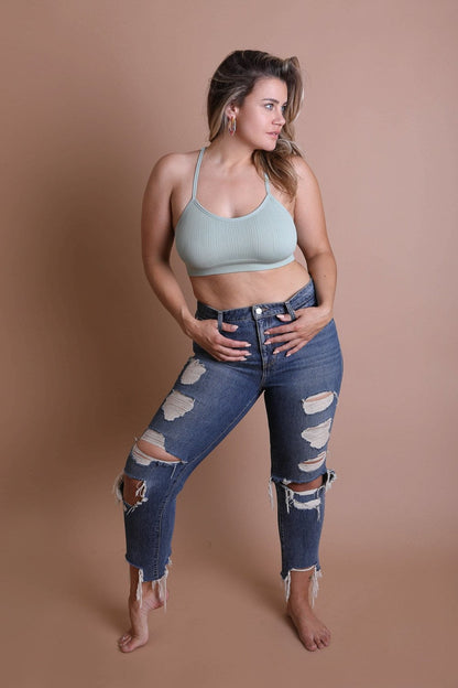 Model wearing plus size tattoo back bralette with high-waisted ripped jeans, showcasing a stylish look