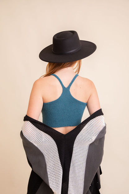 Back view of a model wearing a teal boho racerback brami top paired with a black shawl and wide-brim hat