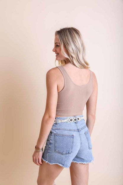 Model wearing a ribbed hook eye brami top in beige with high-waisted denim shorts