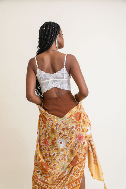 Model wearing a white boho lace bralette with a flowy brown skirt and colorful scarf