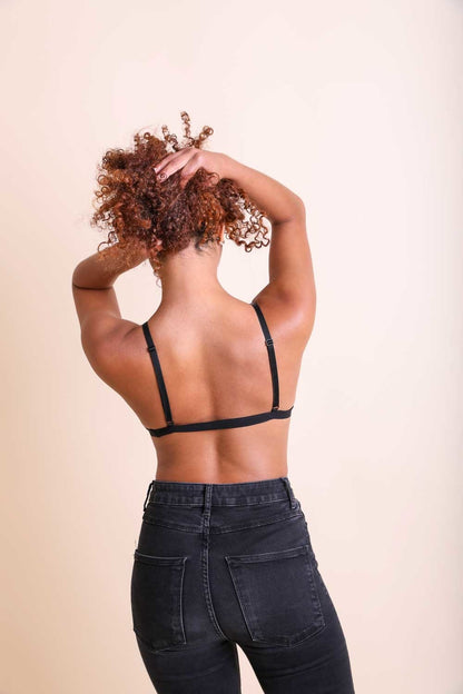 Model wearing a sheer mesh bralette in black, paired with high-waisted jeans, showcasing a stylish back view