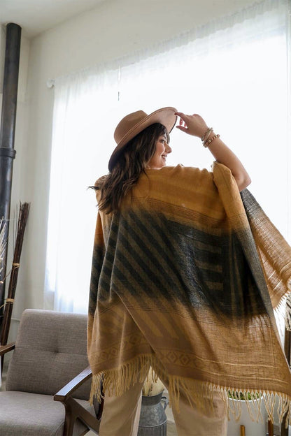 Leto Collection western serape tassel shawl in earthy tones worn by a woman in a stylish setting